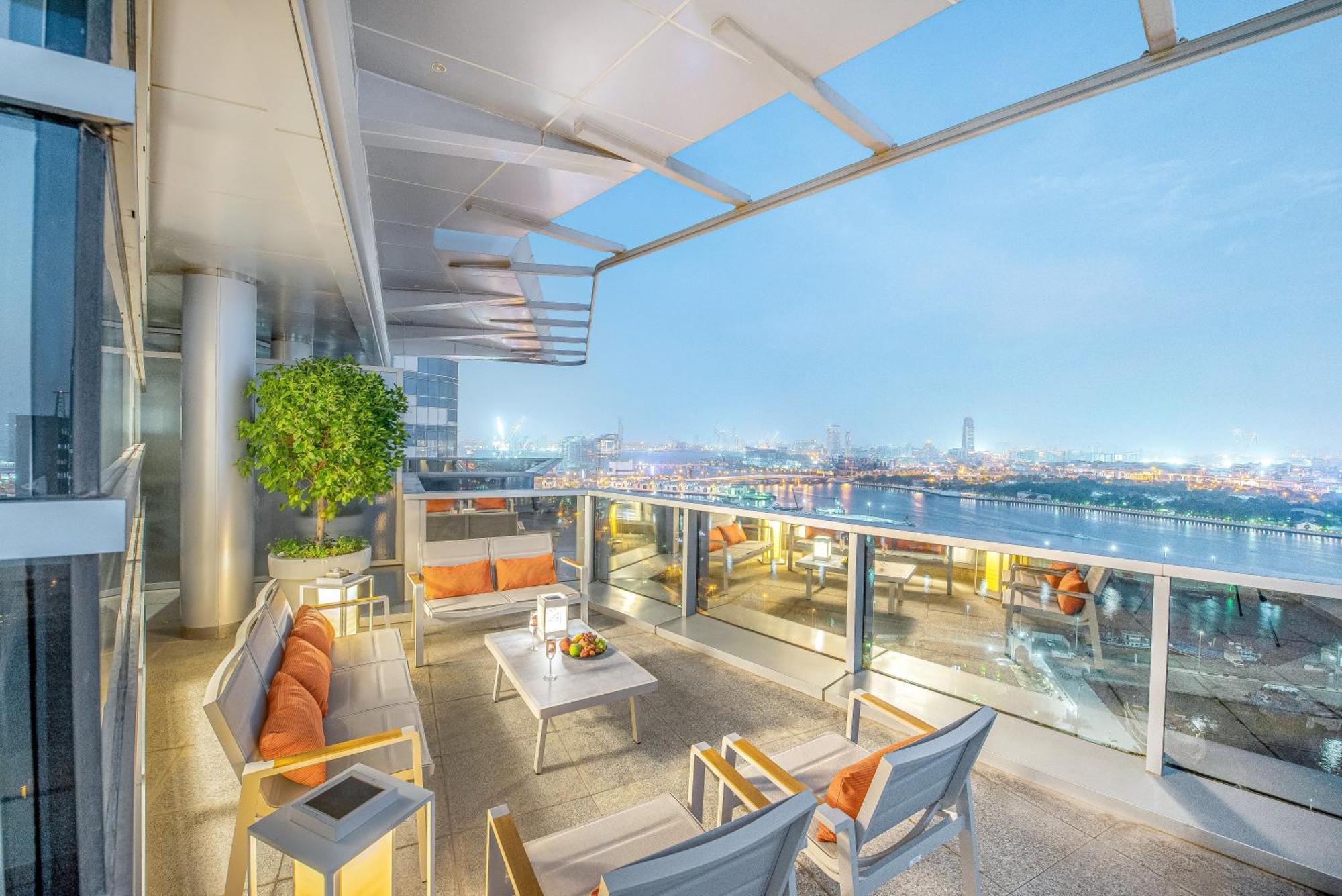 Golden Sands Boutique Hotel-Dubai Creek ภายนอก รูปภาพ The photo depicts a stylish balcony space with a modern design. It features outdoor seating consisting of several chairs and a table, all arranged to provide a comfortable area for relaxation. The seating has soft cushions in warm colors, and the tab