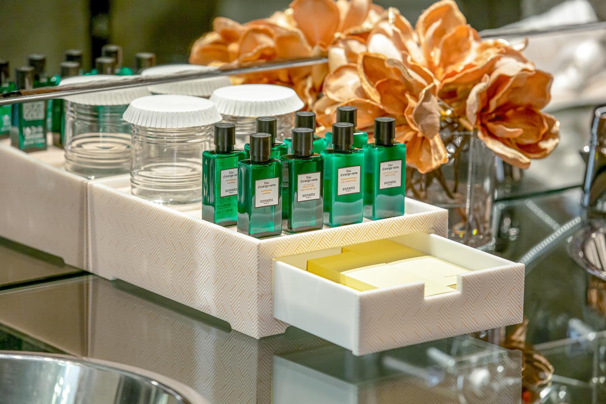 Golden Sands Boutique Hotel-Dubai Creek ภายนอก รูปภาพ The photo shows a neatly arranged tray featuring several small green glass bottles, which likely contain perfumes or essential oils. There are also two clear glass jars and a small white drawer that is slightly open, revealing a yellow item inside. I
