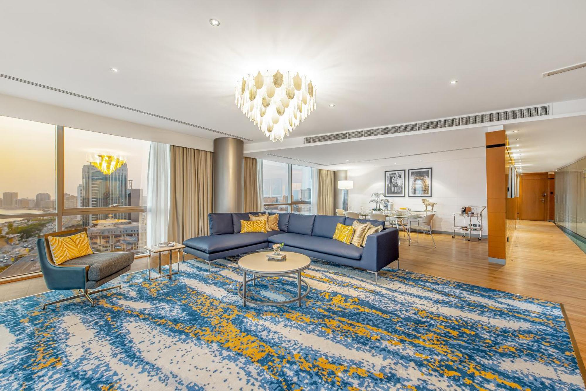 Golden Sands Boutique Hotel-Dubai Creek ภายนอก รูปภาพ The photo shows a modern and stylish living room interior. It features a spacious layout with large windows allowing natural light to fill the space. The flooring is covered with a decorative area rug that displays a vibrant design in blue and yellow